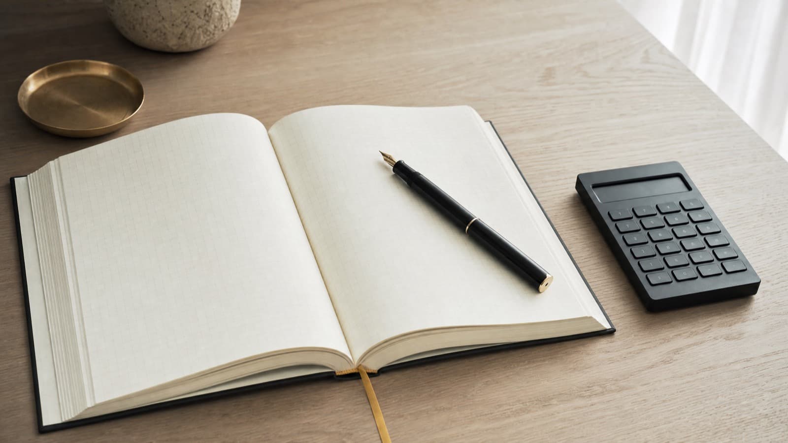 ノートと電卓が置かれた机。結婚相談所の費用を書き出して整理するイメージ